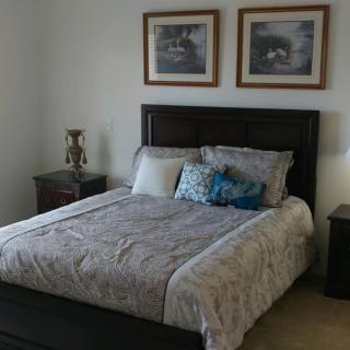 A cozy bedroom featuring a neatly made bed with decorative pillows, flanked by two nightstands and table lamps.