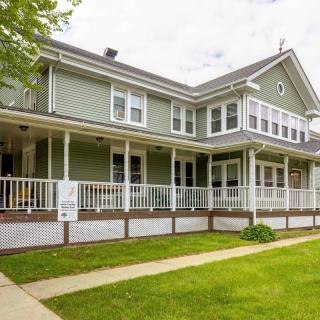 A two-story residential house with a large porch and well-kept lawn.