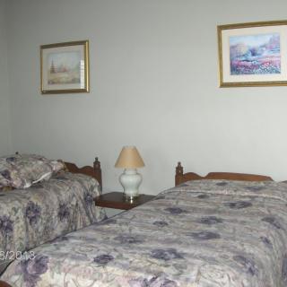 A cozy bedroom with two twin beds featuring floral bedding and wall art.