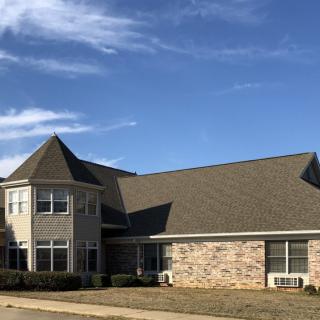 A residential house with a brick exterior and a conical roof feature.