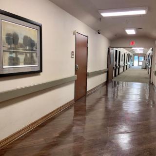 A long hallway in a hospital with shiny flooring and artwork on the walls.