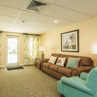 A cozy living room with a sofa, armchair, and large window adorned with curtains.