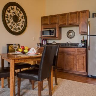 A cozy kitchen and dining area featuring wood cabinets and a dining table with leather chairs.