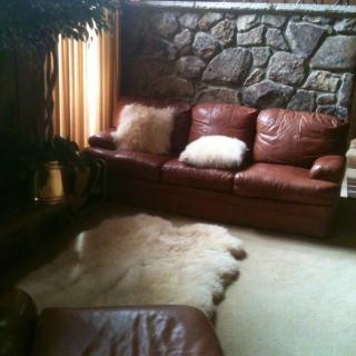 A cozy living room with a leather couch and stone wall.