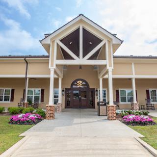 A welcoming entrance to a beautifully designed community center, featuring landscaped gardens and vibrant flowers.