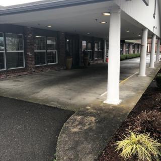 A covered building entrance with white columns and landscaping.