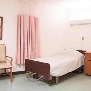 A simple and clean hospital patient room featuring a bed, chair, and curtains.