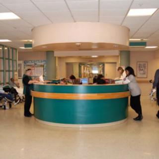 A busy nurses station in a hospital with staff attending to patients and paperwork.