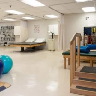 A rehabilitation room equipped with therapy equipment, including exercise balls, treatment tables, and stairs.