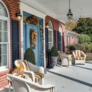 A cozy front porch with wicker chairs and a decorated blue door.