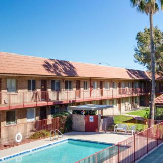 A sunny day at a residential apartment complex with a swimming pool and palm trees.