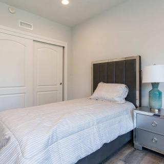 A modern minimalist bedroom with a single bed and nightstand.