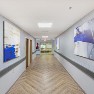 A modern hospital hallway featuring artwork on the walls and clean oak flooring.