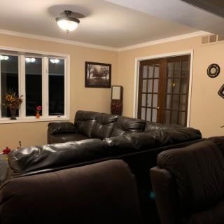 A cozy living room with a dark leather couch and large windows.