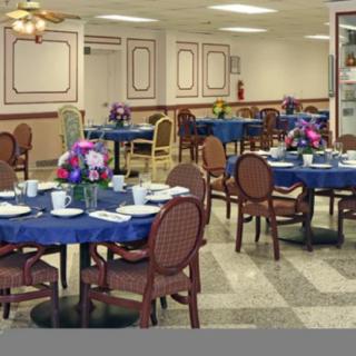 An inviting dining area with tables set for guests, featuring floral decorations and elegant table settings.