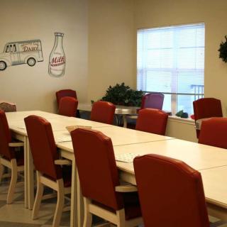 A long dining table with red chairs in a room featuring wall art and a window.