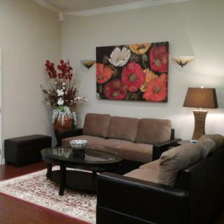 A cozy living room with a brown sofa, floral artwork, and elegant decor.