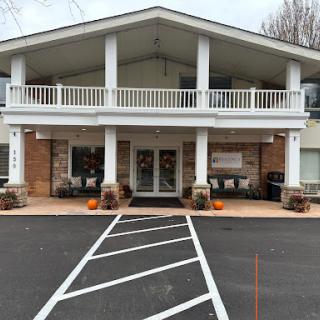 A charming two-story building with a welcoming front entrance and balcony, surrounded by seasonal decorations.