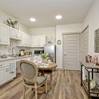 A modern kitchen with white cabinets, wood flooring, and a cozy dining area.