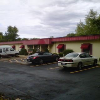 A view of a motel with several parked vehicles under a cloudy sky.