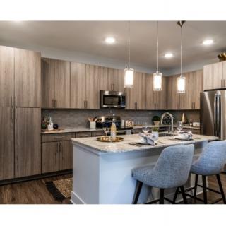A modern kitchen with a central island, pendant lighting, and sleek cabinetry.