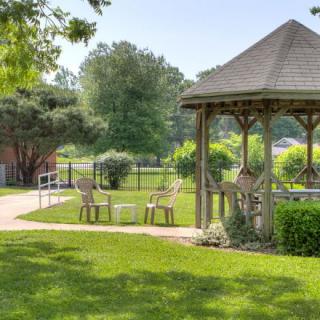 A peaceful garden with a gazebo, surrounded by lush greenery and outdoor seating.
