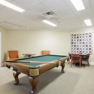 A game room featuring a pool table, chairs, and a decorative wall panel.
