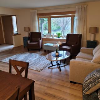 A cozy living room with comfortable seating and large windows overlooking a garden.