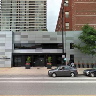 A street view of a modern city building with cars parked in front.
