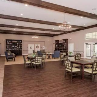 A spacious interior dining area with wooden floors, elegant furniture, ceiling beams, and ambient lighting.