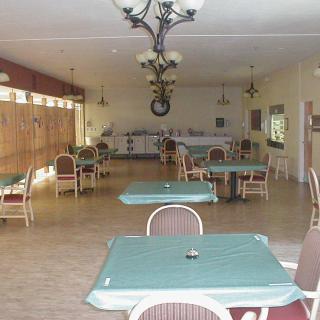 An empty dining area with neatly arranged tables and chairs, featuring a chandelier.