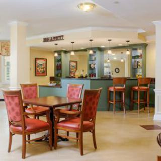 A cozy lobby with a seating area and bar counter, featuring elegant tables and chairs.