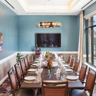 An elegantly set dining room with a long table and chairs, featuring stylish interior decor.