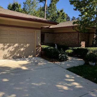 A residential house with a driveway and garage, surrounded by trees.