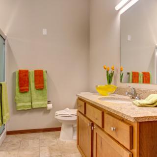 A modern bathroom with wooden cabinetry and colorful towels.
