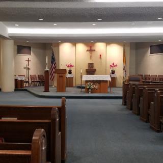 The serene interior of a church featuring an altar and wooden pews.