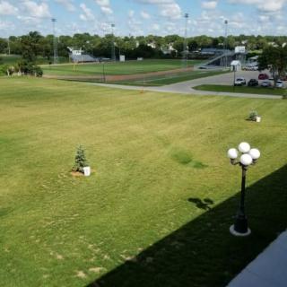 A spacious park area with a sports field and lamp posts under a clear sky.