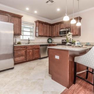 A modern kitchen featuring wooden cabinets, an island, and stainless steel appliances.