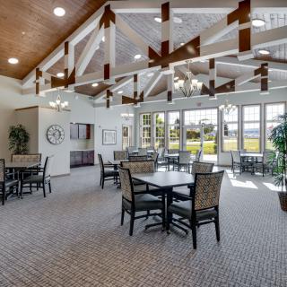 A spacious dining area with large windows and high ceilings adorned with wooden beams and chandeliers.