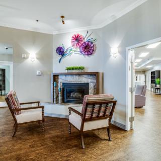 A modern lounge area featuring a fireplace, two armchairs, and decorative wall art.