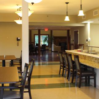 An empty dining area with neatly arranged tables and chairs, featuring modern lighting.