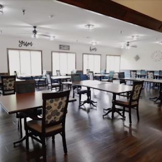 A spacious dining area featuring neatly arranged tables and chairs, illuminated by natural light from large windows.