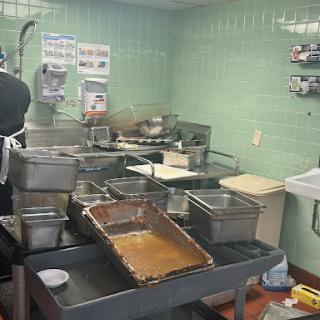 A busy industrial kitchen setup with various metal containers and cooking equipment.