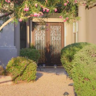 A welcoming front door surrounded by lush green bushes and flowering plants.