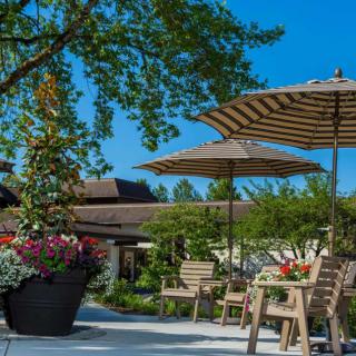 A serene outdoor patio with striped umbrellas, wooden chairs, and vibrant flower arrangements.