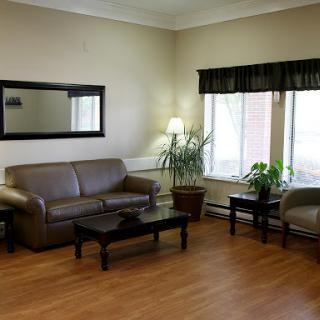 A cozy living room featuring a brown leather sofa, coffee table, and natural lighting from large windows.