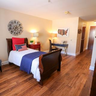 A cozy bedroom with a single bed, wooden flooring, and decorative elements.