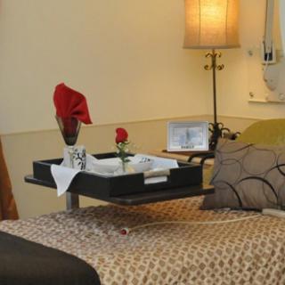 A cozy hotel room with a breakfast tray and a rose on the bed.