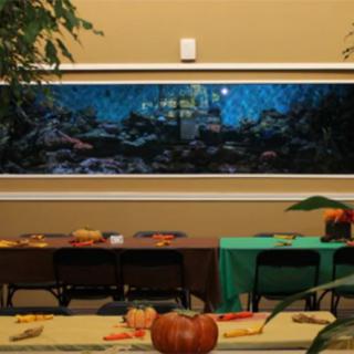 An indoor setting with tables decorated for autumn, featuring pumpkins and an artwork on the wall.