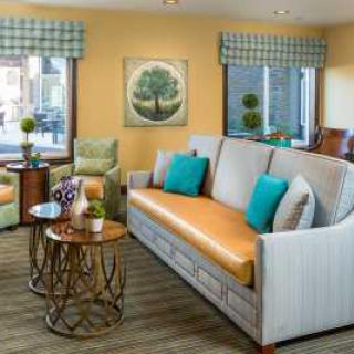 A cozy living room with stylish furniture and decor, featuring a large sofa, colorful cushions, and modern artwork.